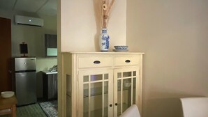 Un comedor con un armario blanco, un florero con plantas secas y una mesa.