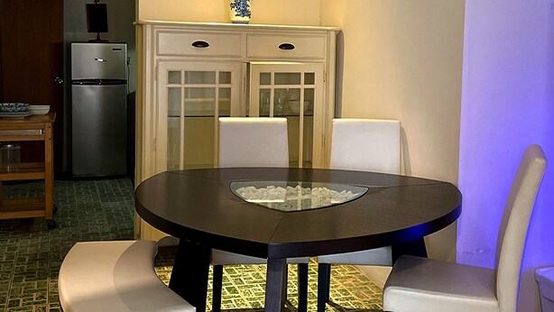 Un comedor con una mesa redonda, cuatro sillas y un aparador con puertas de vidrio.