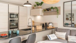 Una cocina moderna con electrodomésticos integrados, una isla central y un comedor con sofá y sillas.