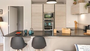 Una cocina moderna con una isla central, una lámpara colgante y un horno empotrado.