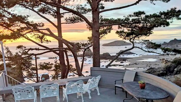 A terrace with outdoor seating, overlooking a beach and ocean at sunset. - Sparkling Clean & Private! Ocean Views! Two Full Bathrooms! [6n7] (Brookings)