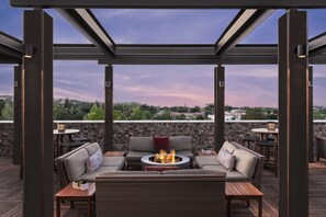 Un espace extérieur aménagé en terrasse, avec un foyer, des sièges et une vue sur le paysage urbain.