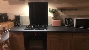 Une cuisine équipée d’une cuisinière noire, d’un four à micro-ondes, d’un grille-pain et d’une machine à café.