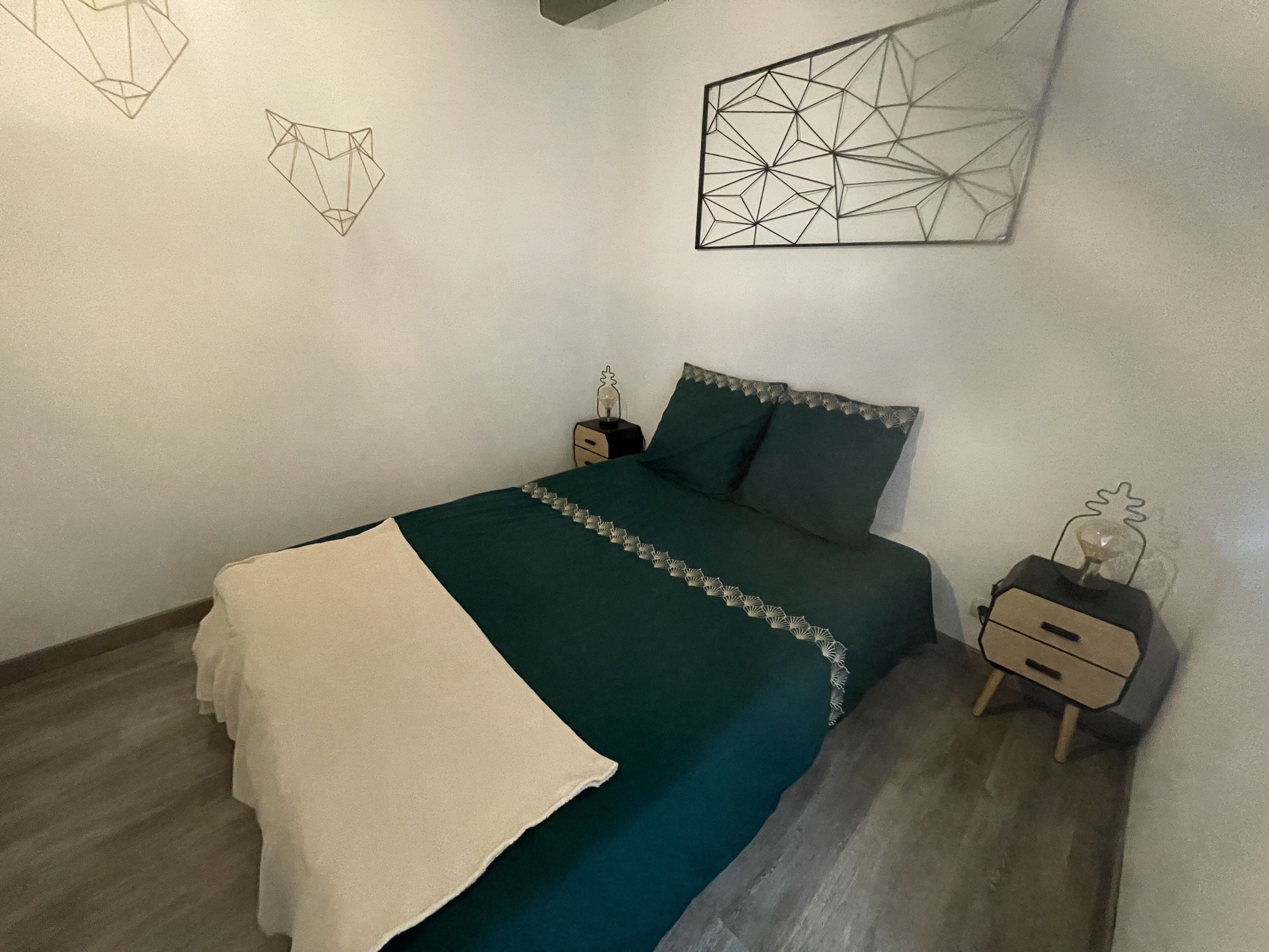 A bedroom with a bed, nightstands, a dresser, and geometric wall art.