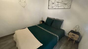 A bedroom with a bed, nightstands, a dresser, and geometric wall art.