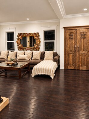 A living room with a sofa set, a coffee table, a large mirror, and a wooden wardrobe.
