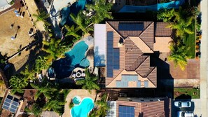 Vue aérienne d’un complexe hôtelier doté de plusieurs piscines, de panneaux solaires et d’un grand bâtiment surmonté d’un toit en tuiles.