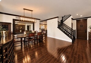 A spacious dining area with a long wooden table and chairs, a chandelier, and a staircase leading to another level. - HUGE Luxury Home..LARGE SALT WATER POOL&SPA.15 min to wineries.  (Murrieta)