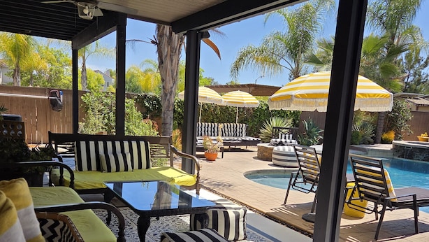 A covered patio with a pool, outdoor furniture, and a view of the backyard.