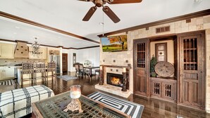 A spacious living room with a fireplace, a dining area, and a kitchen.