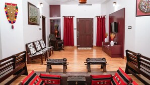 Un salon avec un plancher en bois, des rideaux rouges, un téléviseur et une cheminée.