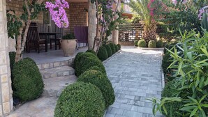 A patio area with a stone pathway, potted plants, and a seating area with a table and chairs. - Comfortable one bedroom apartment 2+1
max. for 3 persons (Biograd n/m)