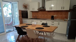 A modern kitchen with white cabinets, a wooden dining table with black placemats, and a black refrigerator. - Comfortable one bedroom apartment 2+1
max. for 3 persons (Biograd n/m)