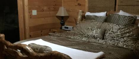 A wooden cabin room with a bed, a lamp, and a ceiling fan.