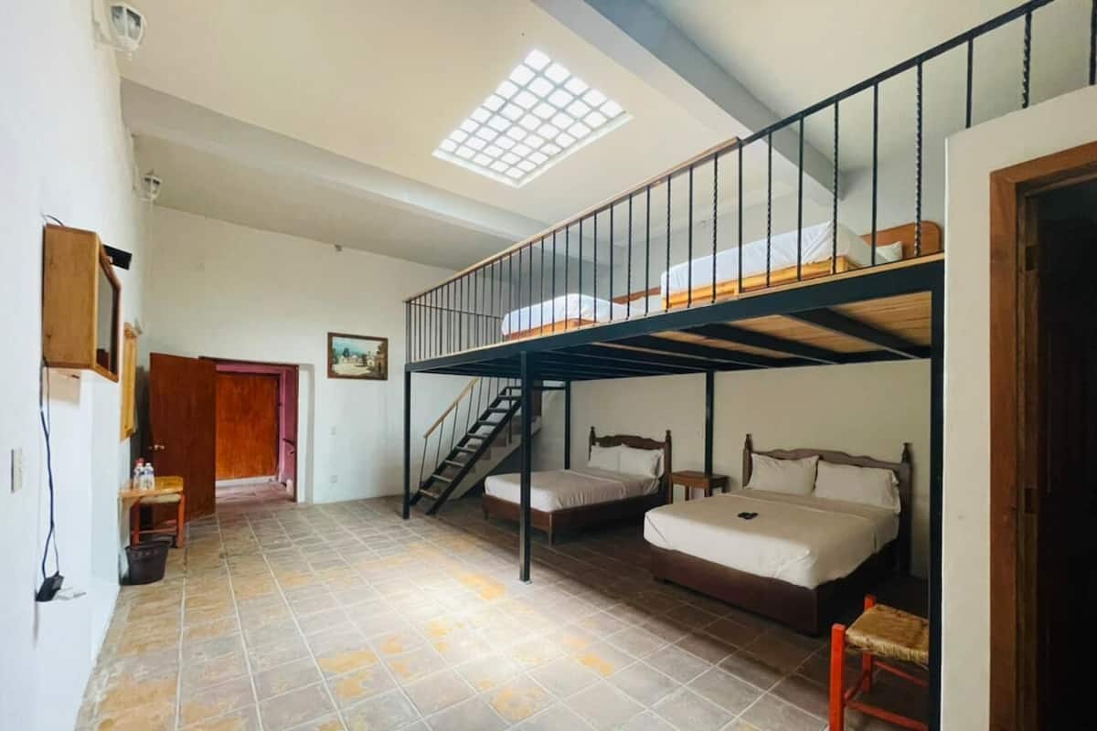 A dormitory-style room with bunk beds, a staircase, and a skylight.