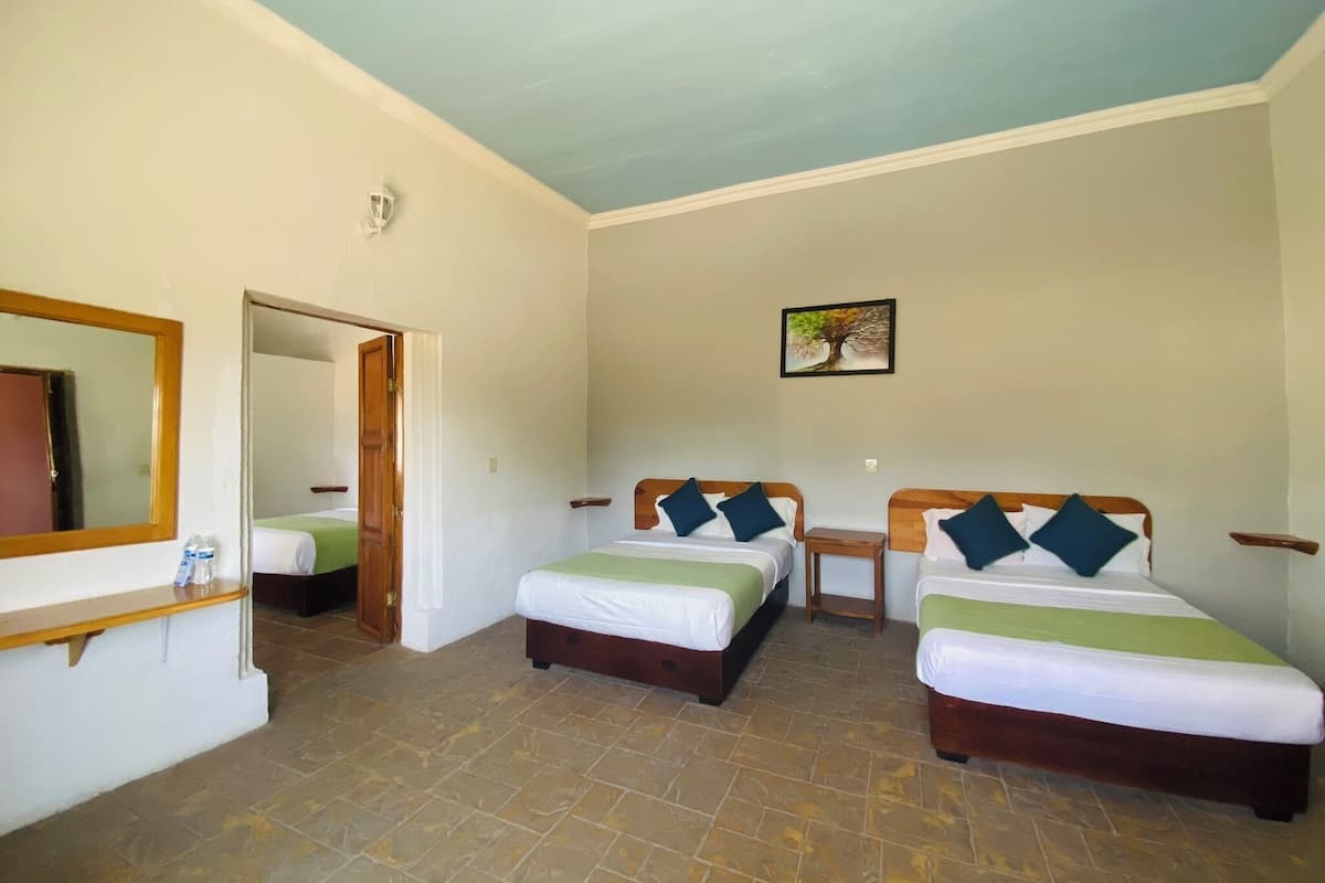 A room with two beds, a mirror, a small table, and a picture on the wall.