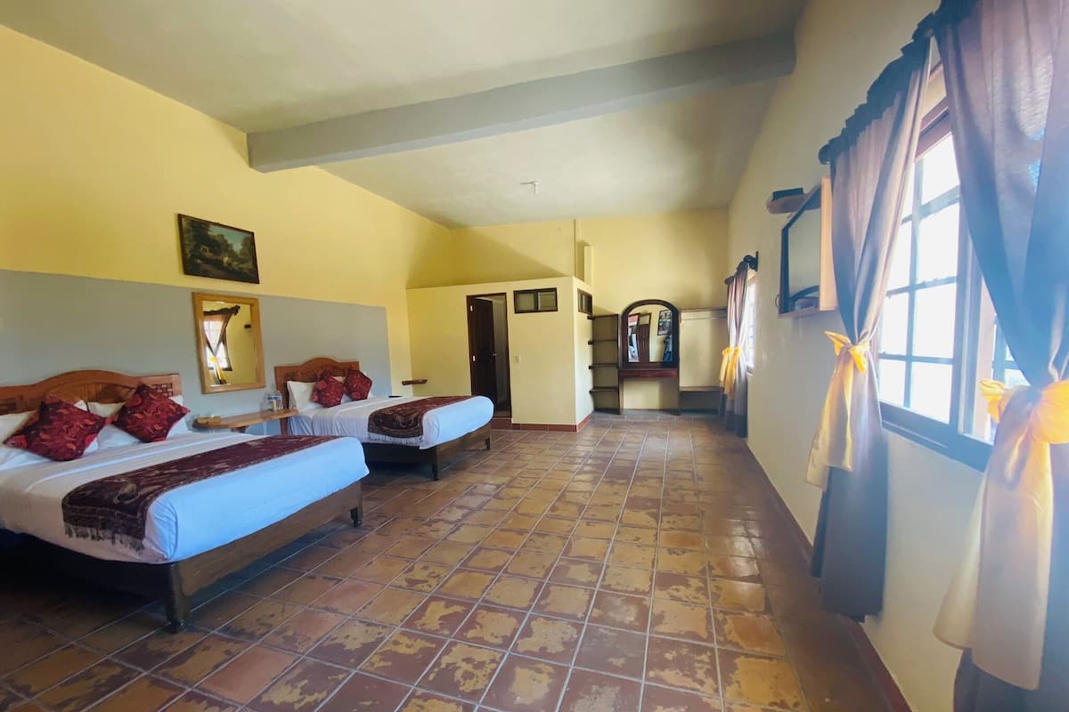 A hotel room with two beds, a large mirror, and a view of the hallway.