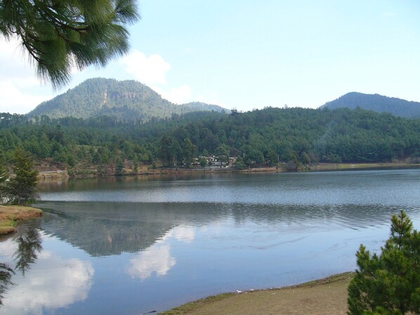 Un lago con una montaña al fondo y un edificio en la orilla.