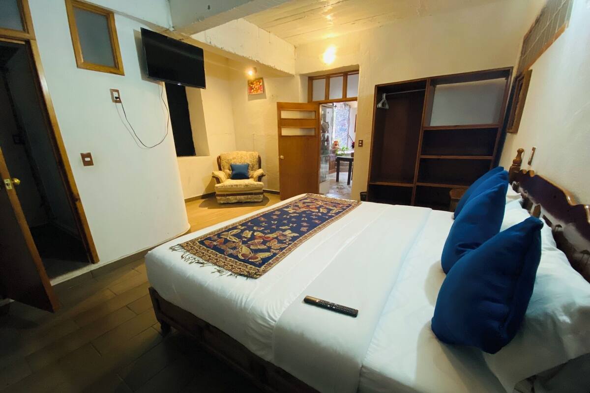 A bedroom with a bed, a chair, a TV, and a wardrobe.