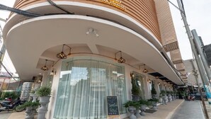 A modern building with a curved facade, large windows, and outdoor seating with potted plants. - One Vientiane Hotel & Restaurant (Vientiane)