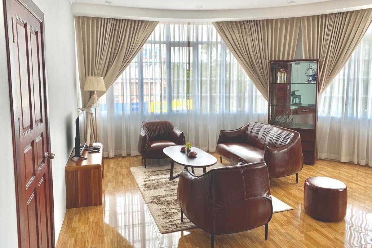 A modern living room with a wooden floor, leather sofas, a coffee table, and a glass cabinet.