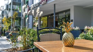 Una mesa de madera con un centro de piña, una silla de mimbre y un edificio con un letrero que dice "Parkhotel".