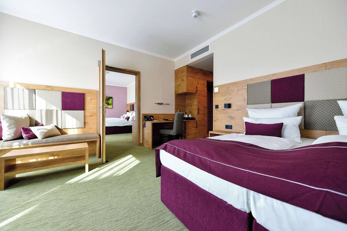 Een hotelkamer met een groot bed, een houten bankje, een bureau en een kledingkast.