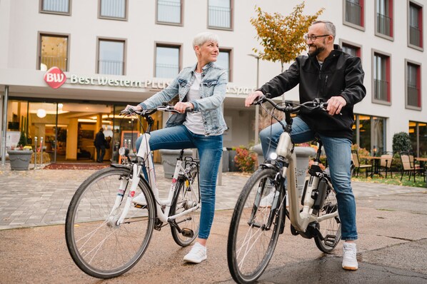 Two people on bicycles in front of a building with a sign that reads "Best Western PLUS." - Best Western Plus Parkhotel & Spa Cottbus (Cottbus)