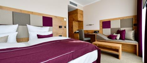 A hotel room with a large bed, a desk, and a seating area.