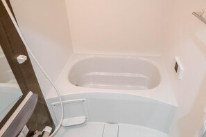 A bathroom with a bathtub, a toilet, and a shower area.