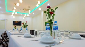 Ein Konferenzraum mit für eine Sitzung gedeckten Tischen, ausgestattet mit Wasserflaschen, Gläsern und einem Fernsehbildschirm.