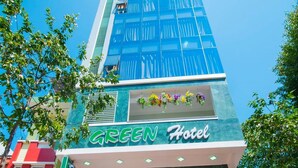 Ein Hotel Eingang mit grüner Fassade, einem Schild mit der Aufschrift "GREEN Hotel" und einer Treppe, die zum Eingang führt.