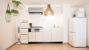 A modern kitchen with white cabinets, a built-in microwave, and a hanging pendant light. - LY INN Ryogoku Annex (Tokyo)