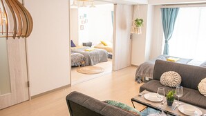 A modern, well-lit apartment with a dining area, a sofa, and a bed in the background. - LY INN Ryogoku Annex (Tokyo)