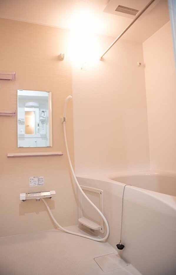 A bathroom with a bathtub, a shower, and a mirror.