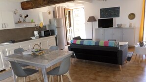 A compact living space with a dining area, kitchenette, and a sofa with a colorful blanket. - Charming apartment between sea and mountains (Sollacaro)