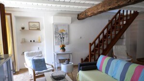 A cozy living room with a wooden staircase, a striped sofa, and a small table with a bowl. - Charming apartment between sea and mountains (Sollacaro)