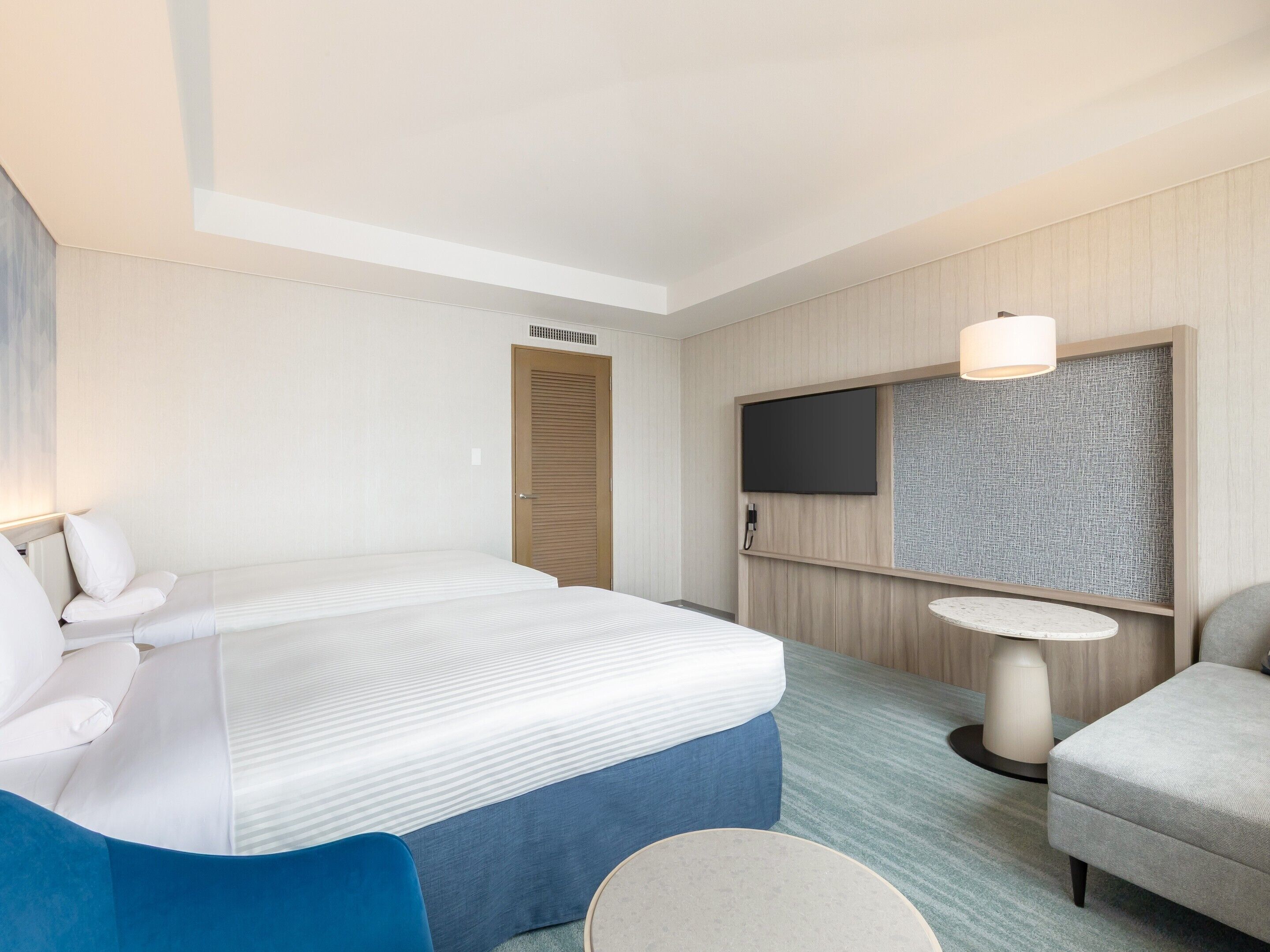 Una habitación de hotel con una cama, un escritorio, una silla, un televisor y una mesita.
