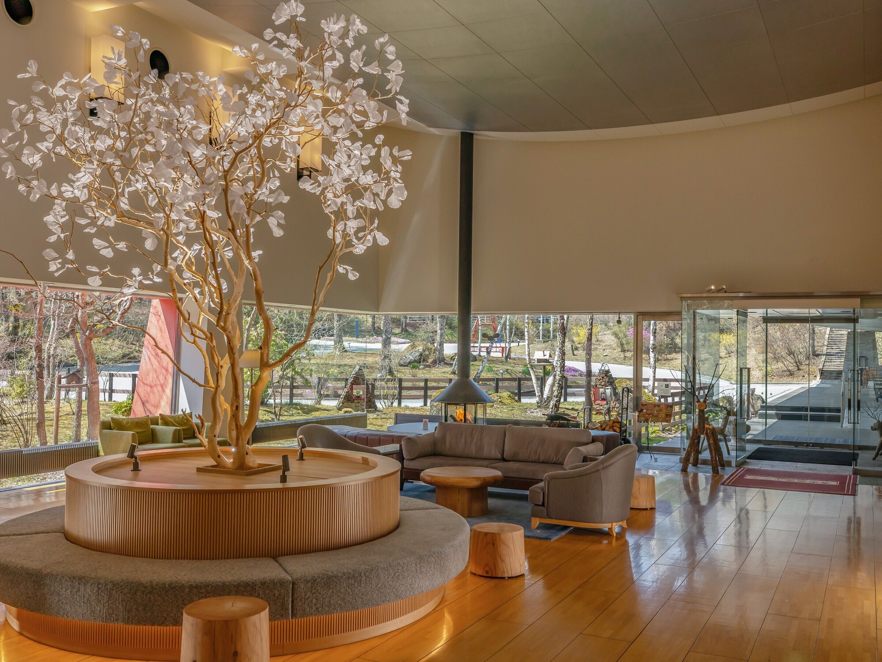 Un interior moderno con una estructura central de madera, arreglos de asientos y ventanas amplias que ofrecen vistas al exterior.
