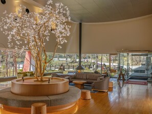 Interior moderno com estrutura central de madeira, disposição de assentos e grandes janelas que oferecem vista para o exterior.