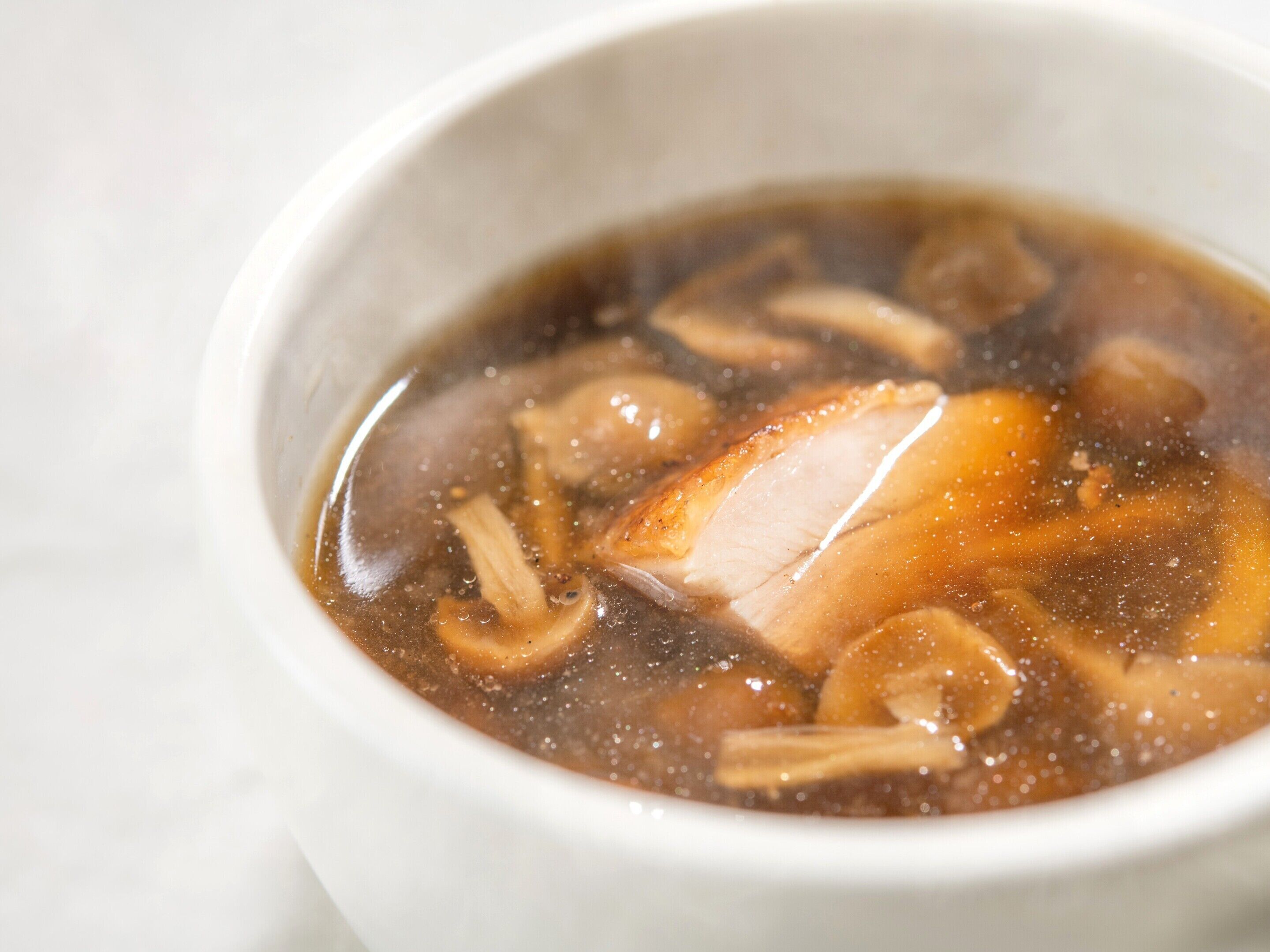 A bowl of soup with visible ingredients like tofu and mushrooms.