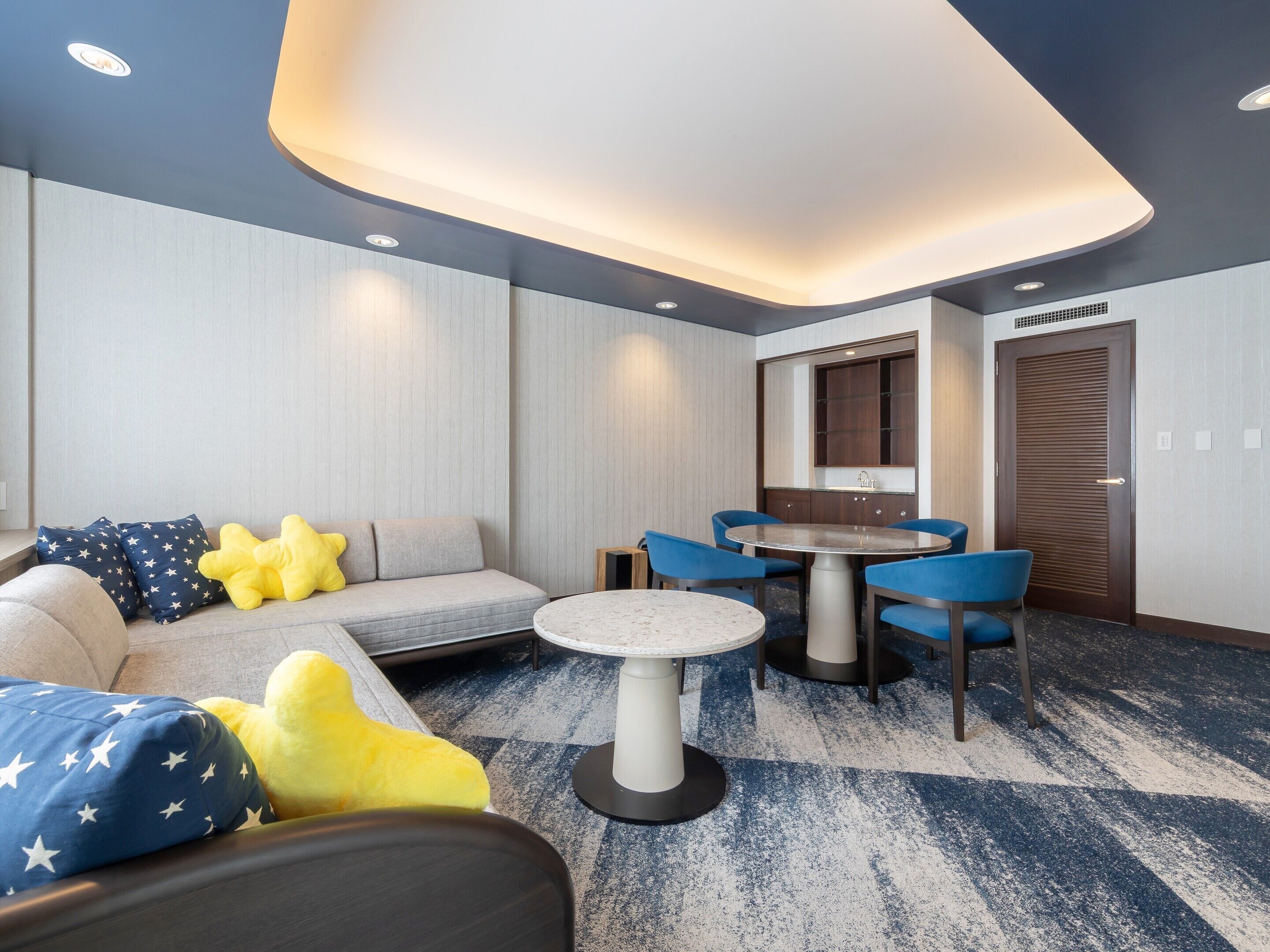 A modern room with a sofa, a round table, and blue chairs.