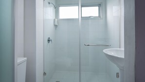 A bathroom with a glass shower enclosure, a toilet, and a pedestal sink. - Eco Inn Lite Nakhon Si Thammarat (Nakhon Si Thammarat)