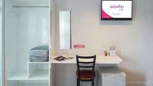 A hotel room with a shower, a desk with a chair, a small fridge, and a TV on the wall. - Eco Inn Lite Nakhon Si Thammarat (Nakhon Si Thammarat)