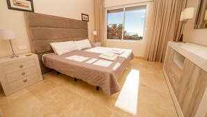 Ein Schlafzimmer mit Bett, Nachttischen, einem Fenster mit Aussicht und einem Badebereich.