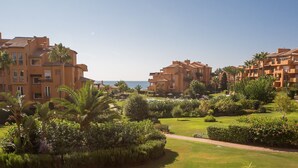 Un resort con varias edificaciones, un jardín bien cuidado y vista al mar.
