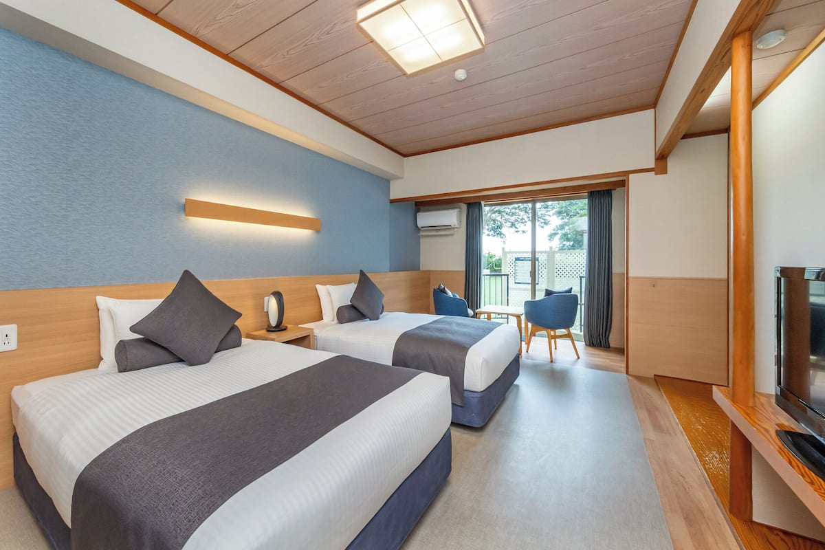 Une chambre d’hôtel avec deux lits, une télévision, un bureau et une chaise.