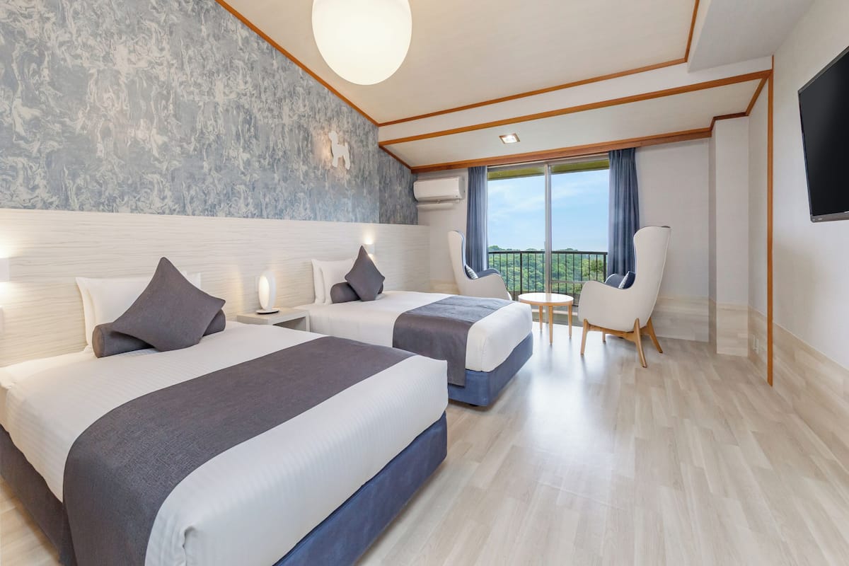 Une chambre d’hôtel moderne avec deux lits, un balcon et une télévision.