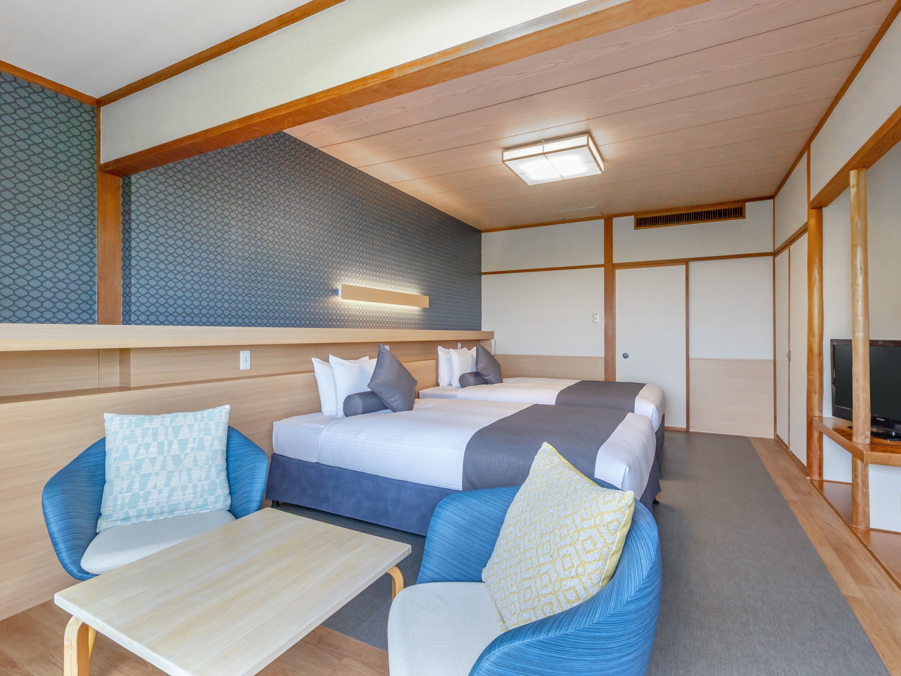 A modern room with two beds, a sofa, a table, and a TV.
