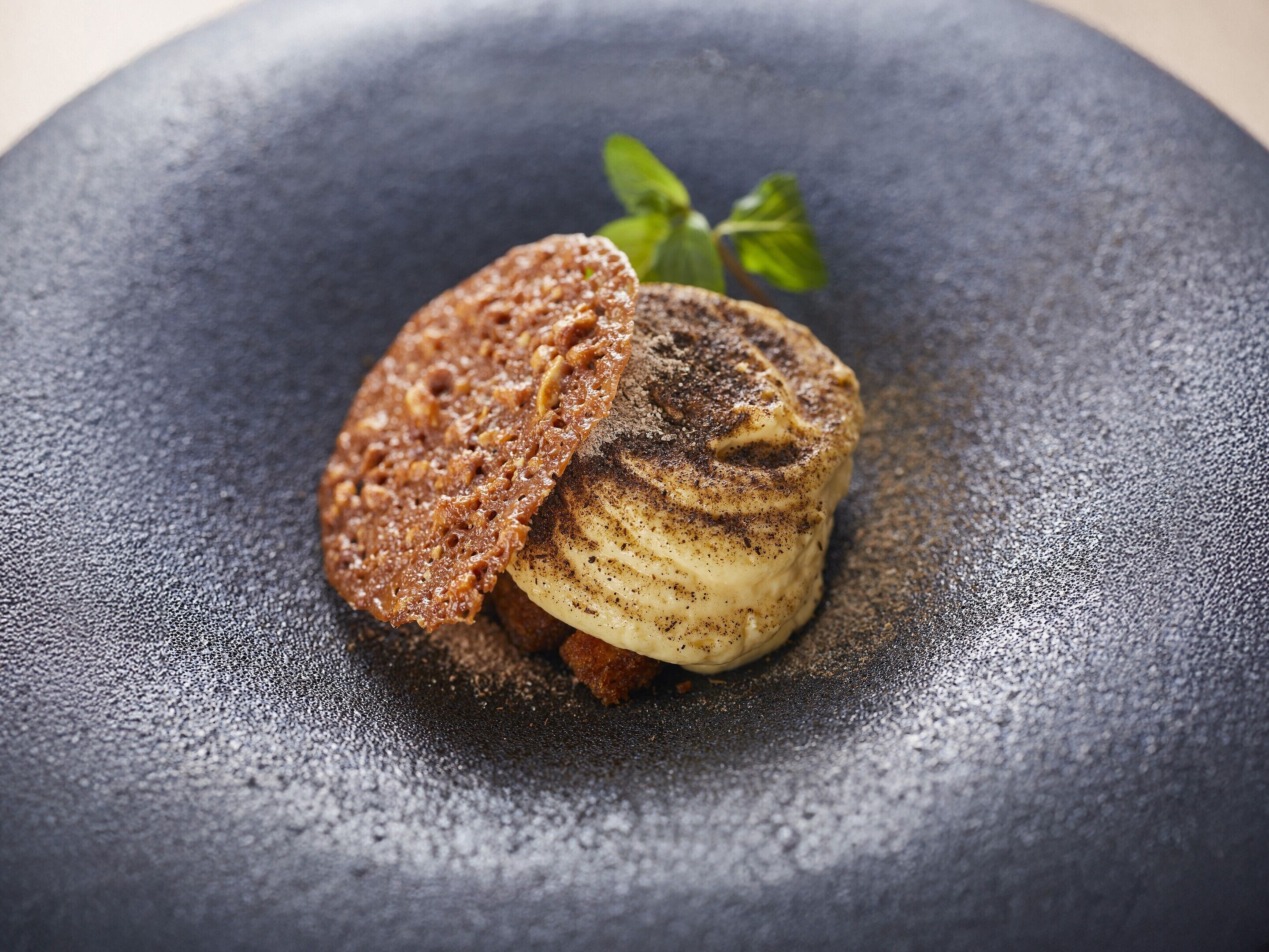 A dessert on a dark plate with a textured surface.
